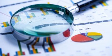 Magnifying glass on charts graphs spreadsheet paper. Financial d